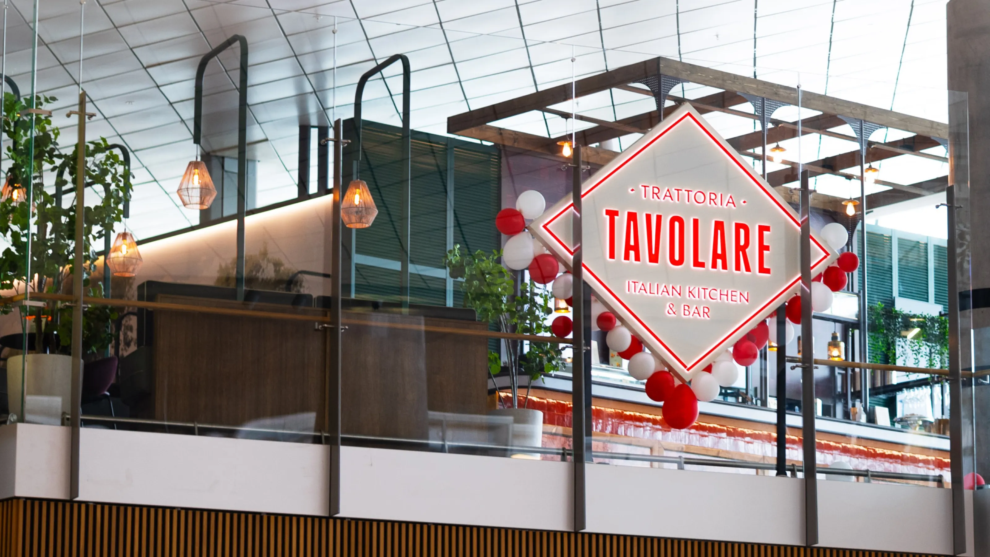Diamond-shaped Trattoria Tavolare sign in red and white above the restaurant at Oslo Airport