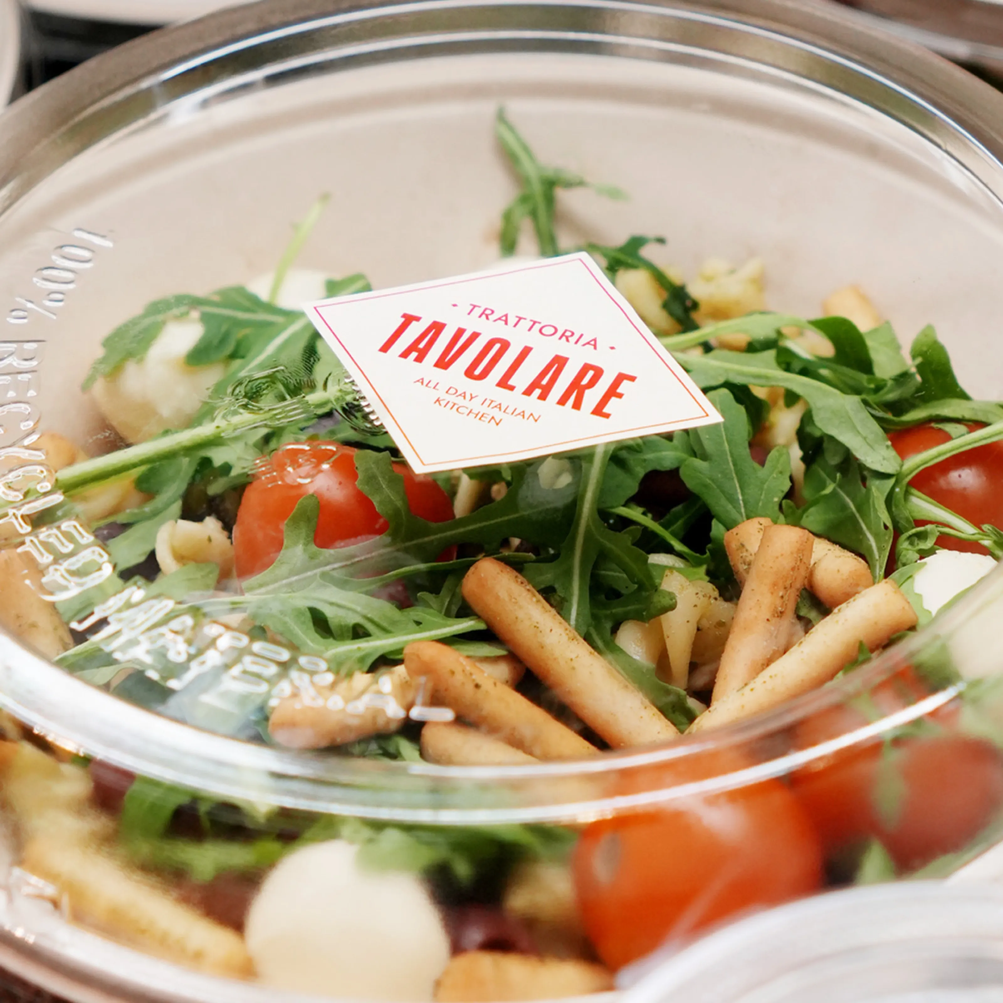 Takeaway salad with rocket, tomatoes, mozzarella and breadsticks, sealed with a Tavolare label