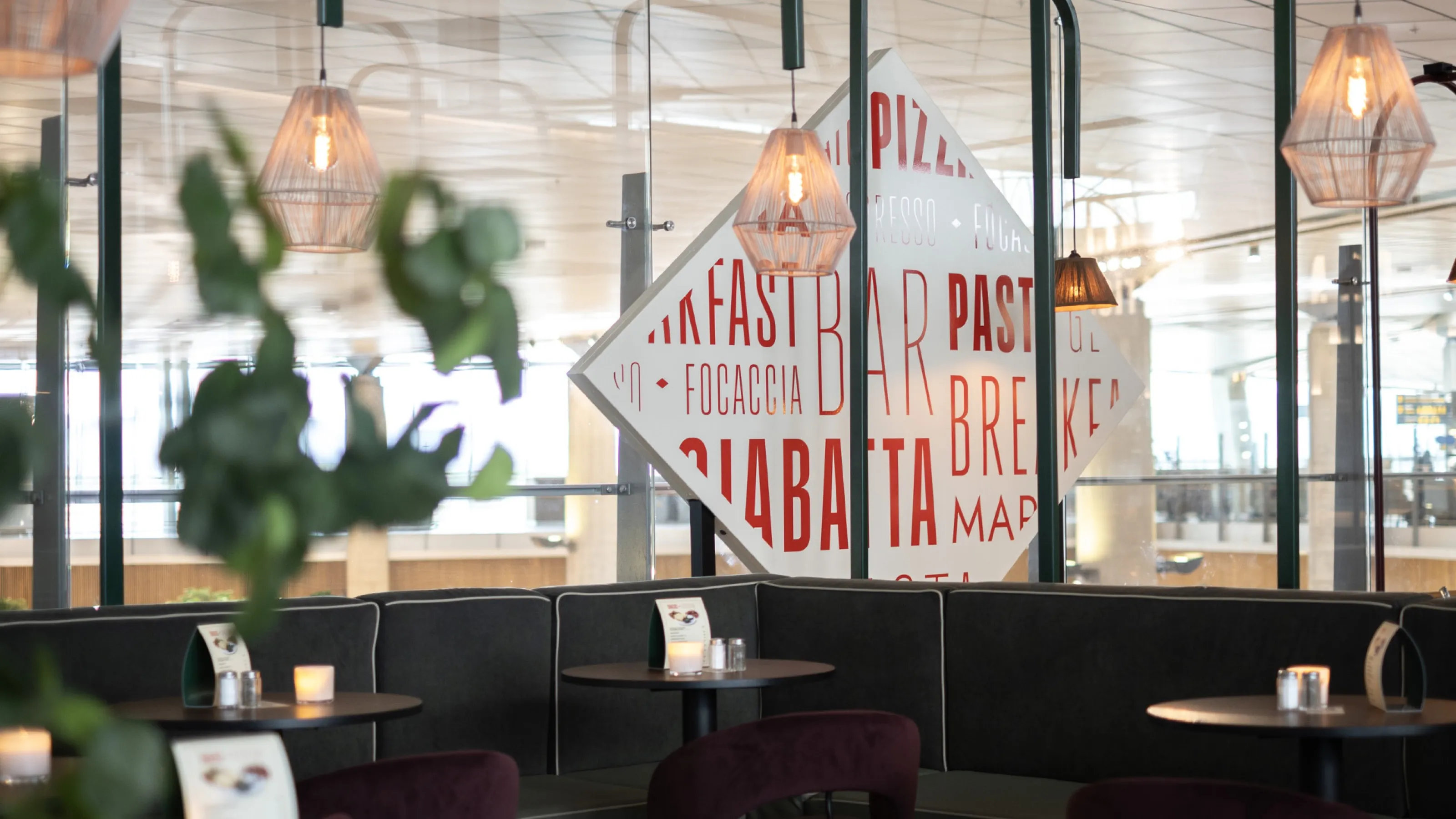 Seating area with copper pendant lamps and a large diamond sign with Italian menu words